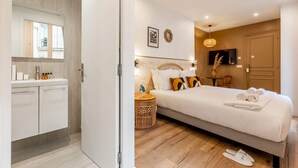 A modern hotel room with a large bed, a bedside table, a mirror, and a TV. - Sweett | Madeleine VI (Paris)