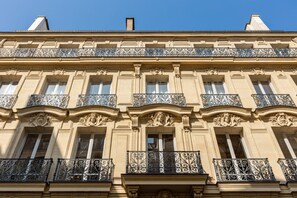 Um edifício com várias andares, varandas ornamentadas e detalhes arquitetônicos clássicos.