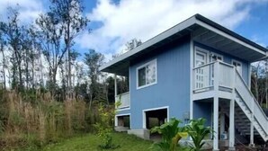 A two-story house with a blue exterior and white trim, surrounded by a grassy yard and a small garden area. - Mountain View Retreat Unit 2 - highly rated on leading vacation rental sites! (Mountain View)
