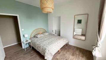 Et soveværelse med seng, et natbord, en lampe, en radiator, et spejl og en pendel.