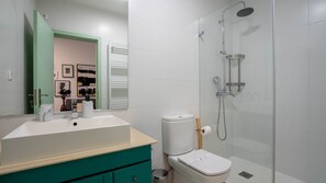 Bathroom features a large sink, separate toilet, and a shower area with a glass-enclosed showerhead.