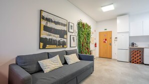 Relax in a stylish waiting area with a sofa, abstract art, and lush greenery.
