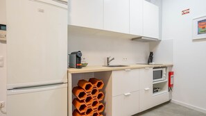Une petite cuisine équipée comprenant une machine à café, un évier, un four à micro-ondes et un meuble de rangement original en forme de nid d’abeilles.