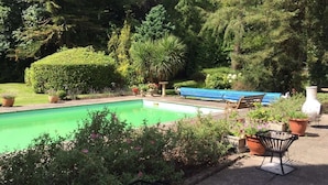 A swimming pool with a blue tarp, surrounded by potted plants and a bench. - Victorian Mannor House with easy London access  (Godalming)