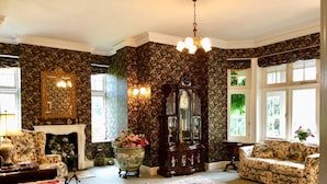 A traditional room with a fireplace, floral wallpaper, a grandfather clock, and patterned rugs. - Victorian Mannor House with easy London access  (Godalming)