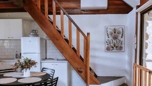 Una cucina moderna con una scala in legno, un'area pranzo con tavolo e sedie, e un lampadario.