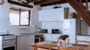 Una cucina con mobili bianchi, un tavolo da pranzo in legno e sedie.