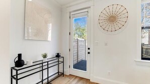 A hallway with a black metal console table, a white door, and a round wall decoration. - Newly Built 3BR Home in Alexandria-Walk to Metro!

 (Alexandria)