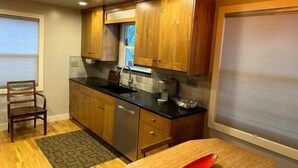 A modern kitchen with wooden cabinets, a black countertop, a dishwasher, and a window with blinds. - ALL NEW - Clean & Modern! Mountain Garden Oasis! (Ogden)