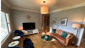 A living room with a TV, sofa, chairs, and a coffee table. - ALL NEW - Clean & Modern! Mountain Garden Oasis! (Ogden)