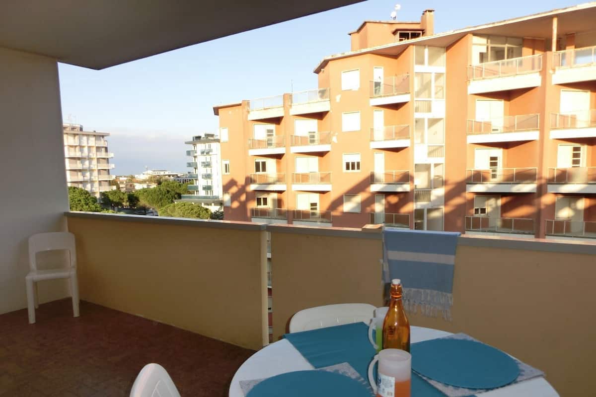 A balcony with a table, chairs, and a bottle.