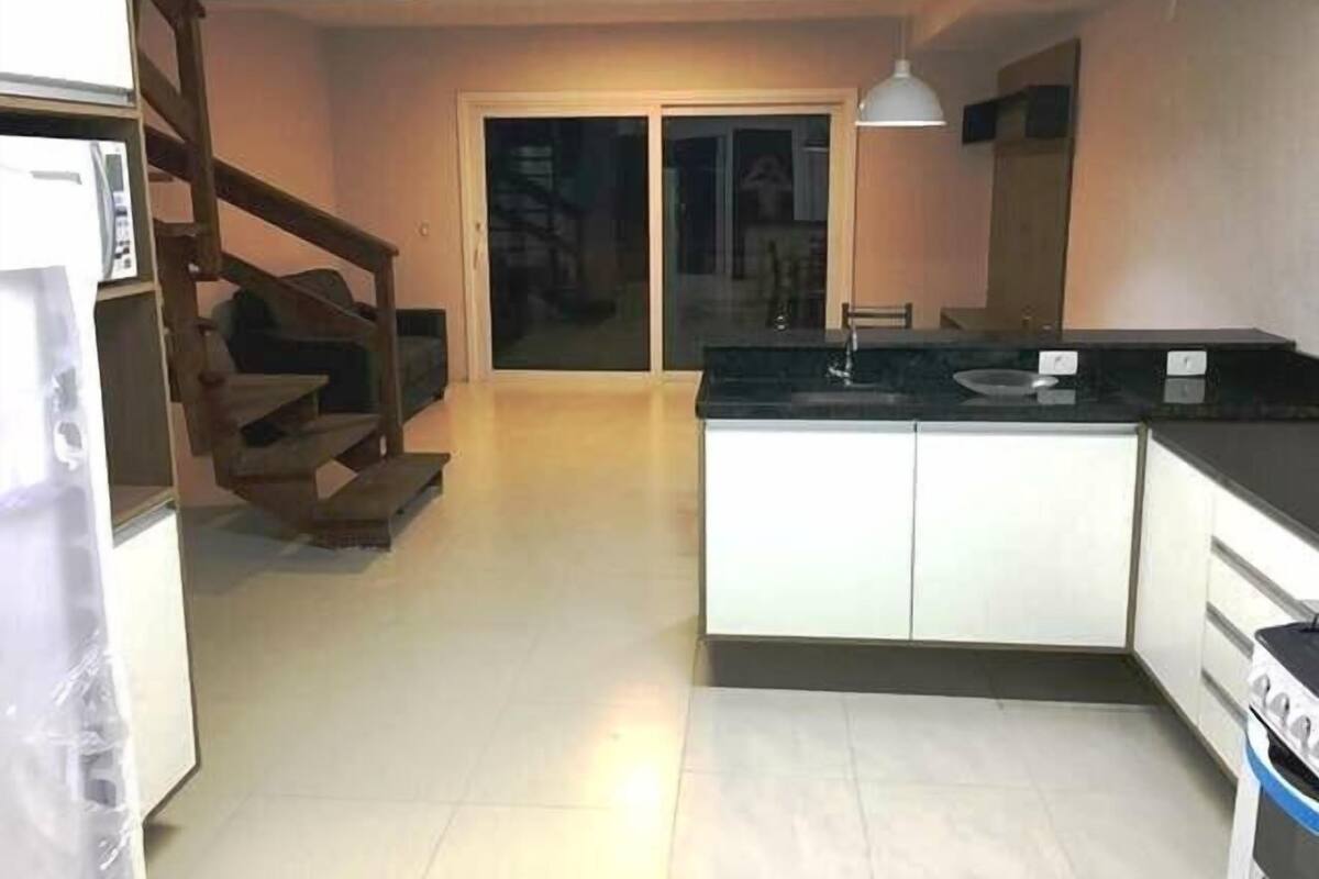 A kitchen with a central island, a built-in oven, and a dining area with a table and chairs.
