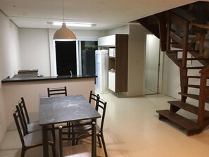 A dining area with a marble table and chairs, a pendant light, and a staircase leading to an upper level. - Residencial Don Vito (Capao da Canoa)