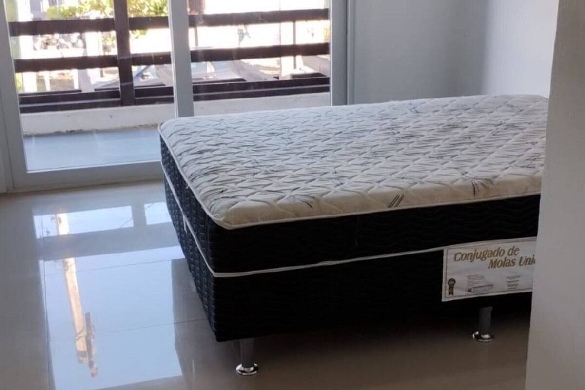 A bedroom with a bed, a sliding glass door to a balcony, and a tiled floor.