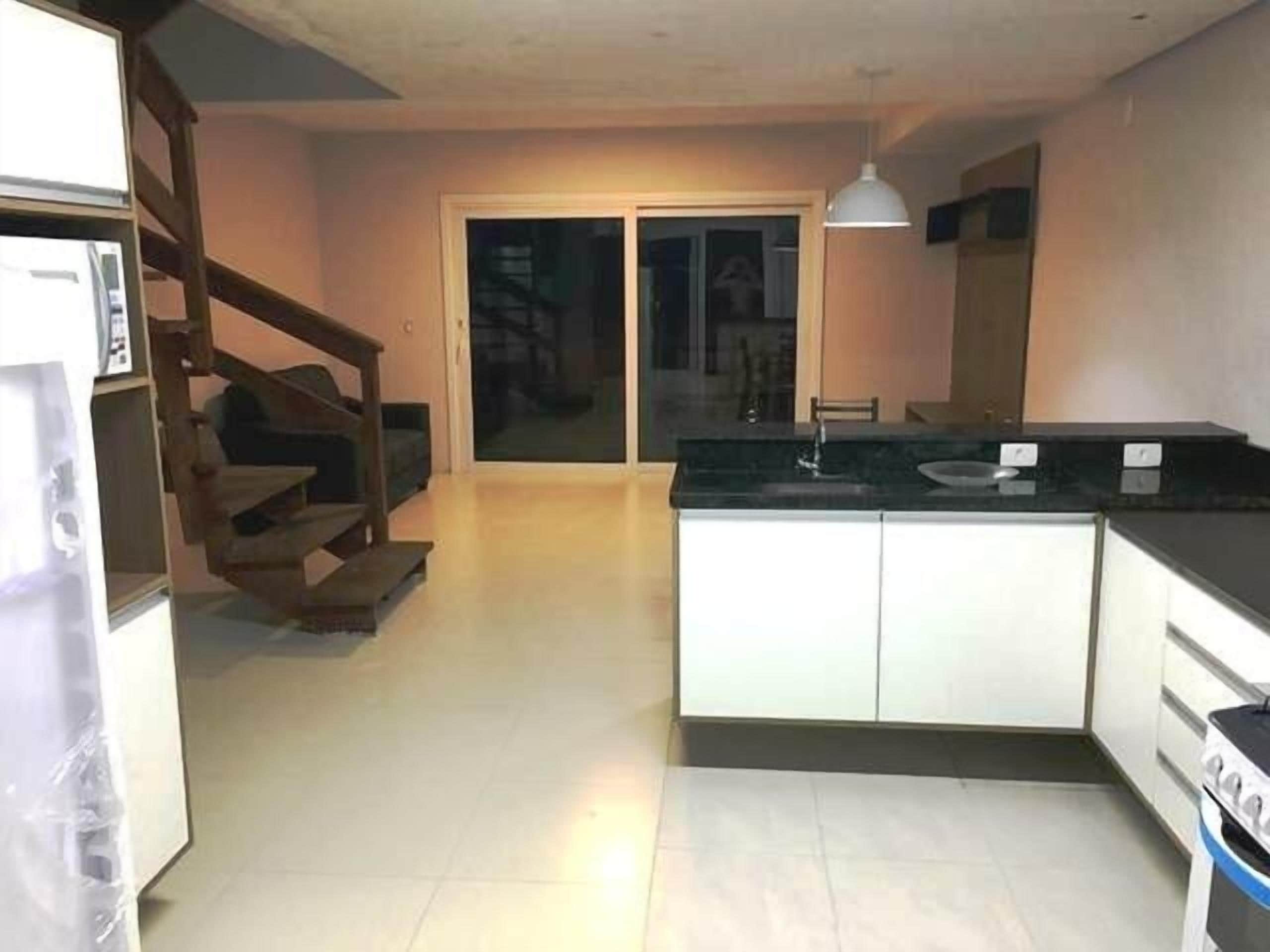 Uma cozinha com ilha central, forno embutido e área de jantar com mesa e cadeiras.