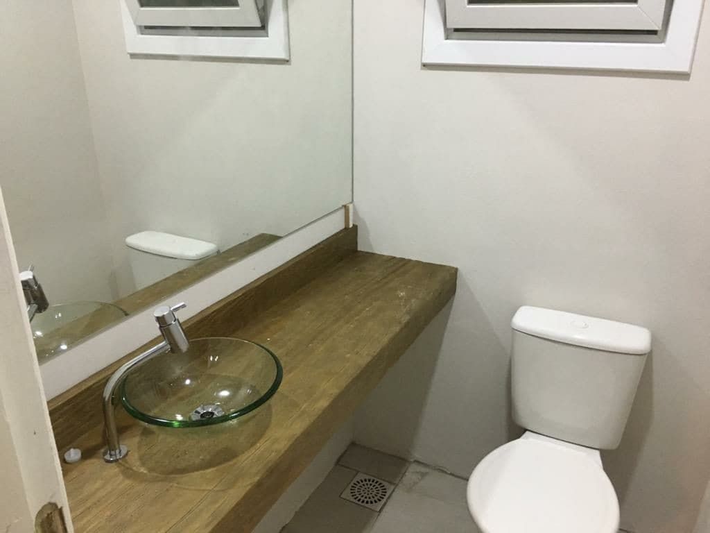 Une salle de bain avec un lavabo en verre, des toilettes blanches et un miroir au-dessus du lavabo.