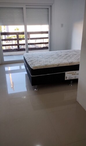 A bedroom with a bed, a sliding glass door to a balcony, and a tiled floor. - Residencial Don Vito (Capao da Canoa)
