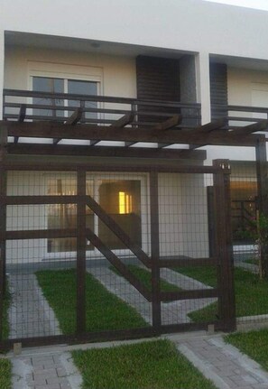 A gated entrance with a metal fence and a wooden pergola. - Residencial Don Vito (Capao da Canoa)
