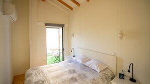 Un dormitorio con cama, mesita de noche, lámpara y ventana con vistas a un jardín.