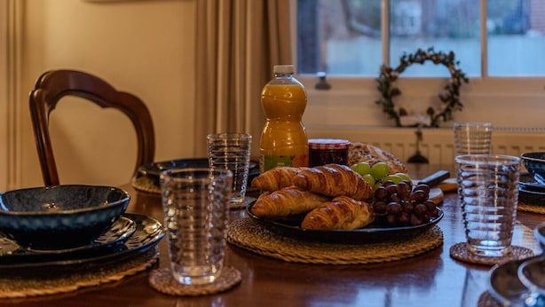 Uma mesa de café da manhã com croissants, uvas e uma garrafa de suco de laranja.