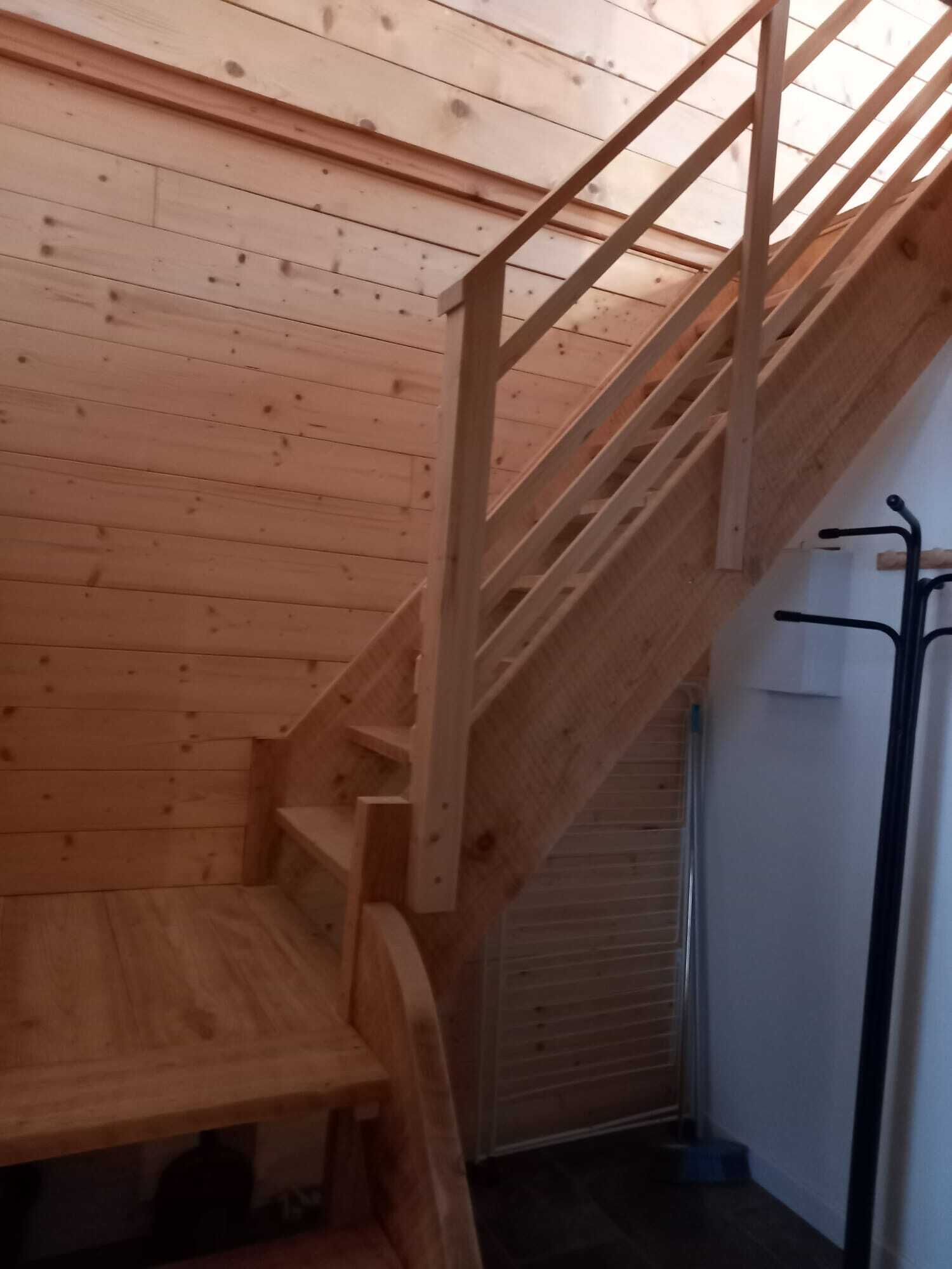 Eine Holztreppe mit Metallgeländer, die zu einer Aussichtsplattform mit einer Bank führt.