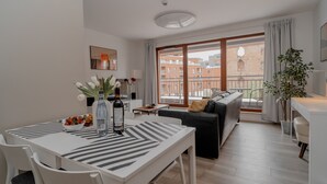 Ein modernes Wohnzimmer mit Esstisch, Sofa und großen Fenstern mit Blick auf Gebäude.