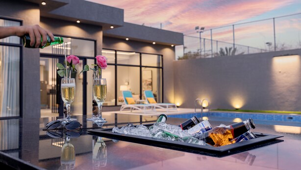 A bar area with a tray of ice, glasses, and bottles, overlooking a pool with lounge chairs. - Riyadh View Resort (Riyadh)