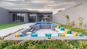 A modern outdoor pool area with a built-in seating area, surrounded by a well-maintained lawn and garden. - Riyadh View Resort (Riyadh)