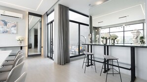 A modern kitchen with a large window, a dining area with a table and chairs, and a bar area with stools. - Riyadh View Resort (Riyadh)
