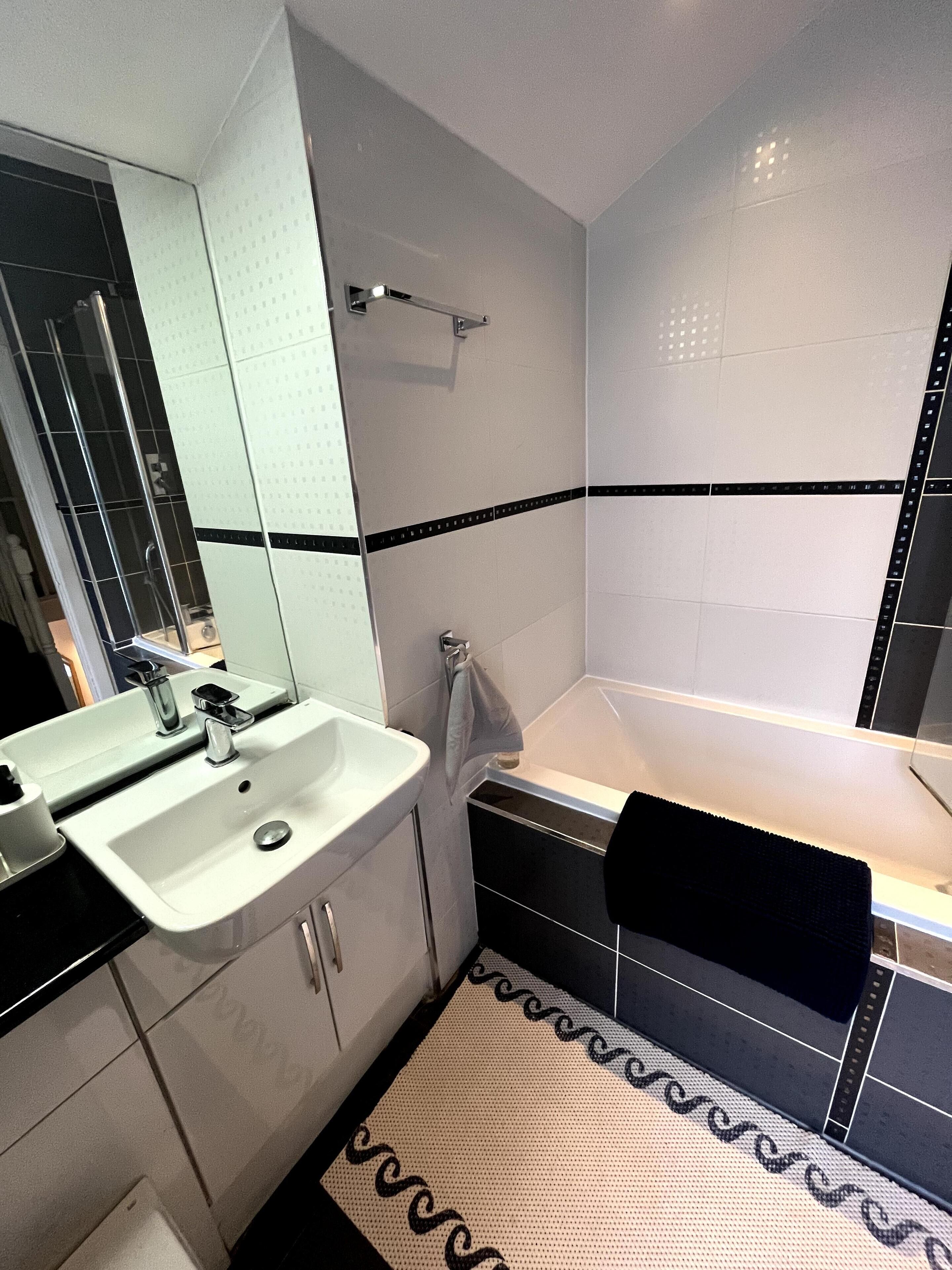 A bathroom with a white sink, a mirror, a towel rack, and a bathtub.