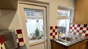 Eine kleine Küche mit Fenster, Spüle und Geschirrgestell.
