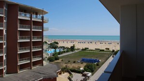 A high-rise building with multiple balconies overlooking a beach with a pool and umbrellas. - Well-equipped 1 Bedroom Flat for up to 5 Guests (San Michele al Tagliamento)