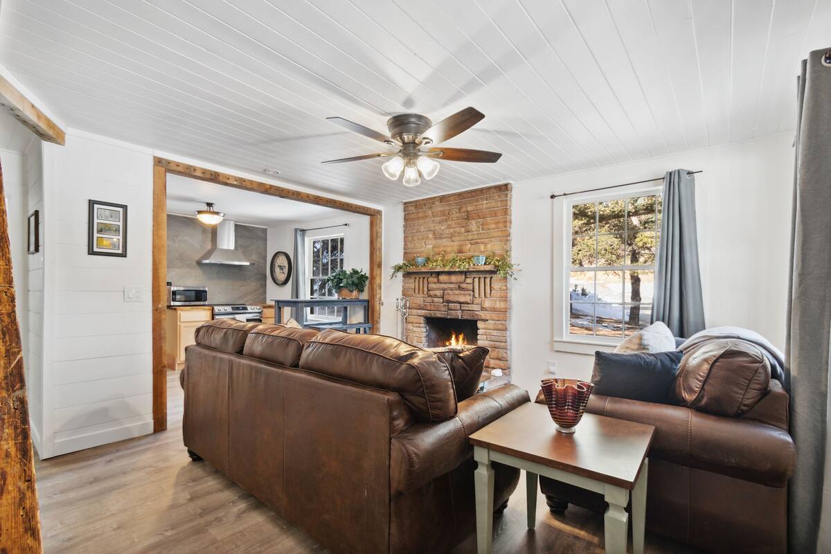 A cozy living room with a fireplace, a sofa, and a dining table.