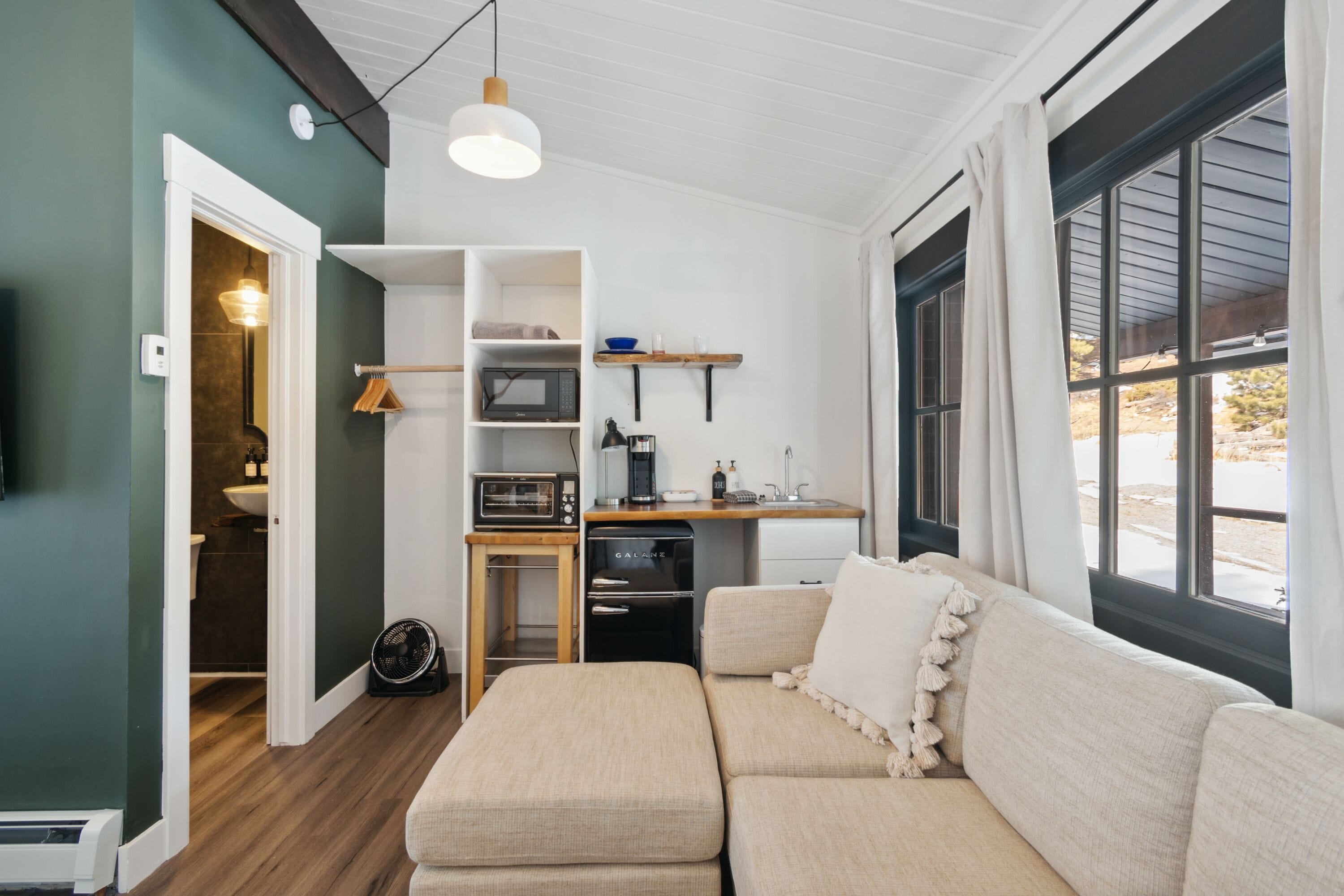 Un espacio habitable compacto con kitchenette, un sofá y zona de comedor.