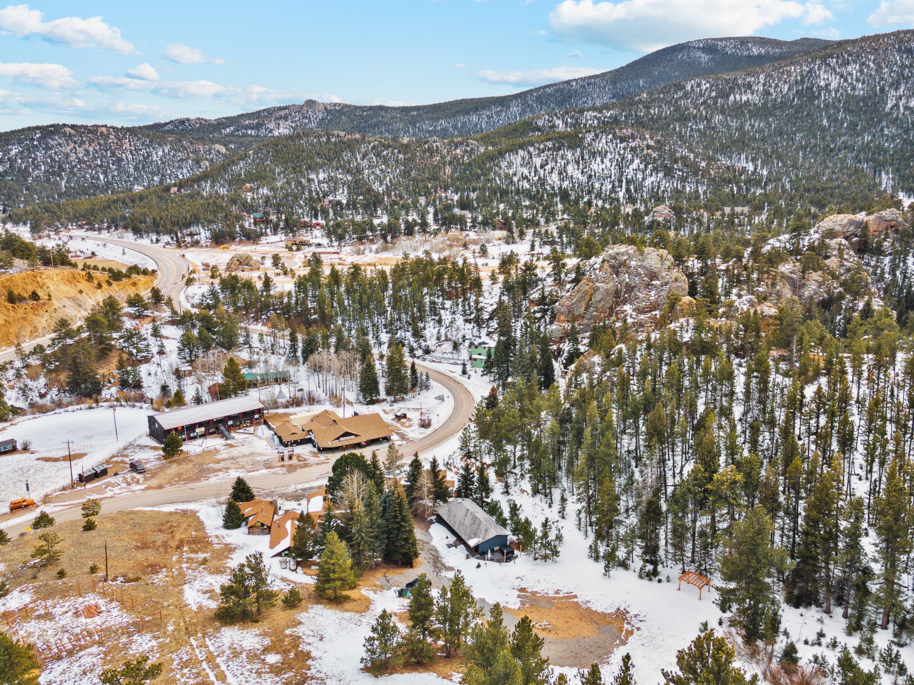 A mountainous area with a road curving through it, surrounded by snow-covered trees and buildings.