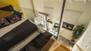 Quarto moderno com uma cama grande, varanda de vidro e vista para a cozinha.