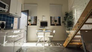 Cozinha moderna com armários brancos, micro-ondas embutido e área de refeições com mesa e cadeiras.