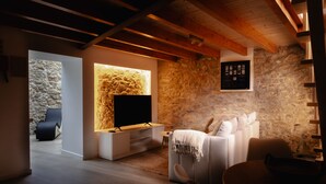Un soggiorno moderno con una parete in pietra, una TV a schermo piatto, un divano e un'area pranzo.