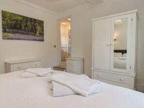 Un dormitorio con cama, armario, mesita de noche, espejo y un cuadro en la pared.