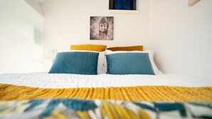 A bed with a patterned bedspread, two pillows, and a wall-mounted picture above the bed. - Ilha D’ouro House S. Vitor II (Porto)