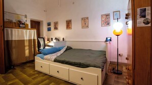 Ein Schlafzimmer mit Bett, Schreibtisch, Stuhl, Lampe und Kleiderschrank.
