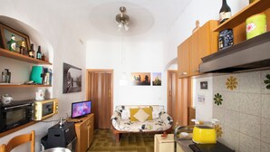 Eine kleine Küche mit Mikrowelle, Toaster und Herd, ein Sofa in der Mitte sowie ein Deckenventilator.