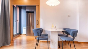 Une cuisine moderne avec un réfrigérateur en acier inoxydable, une table de salle à manger ronde entourée de quatre chaises et un luminaire suspendu.