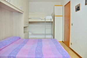 Een slaapkamer met een stapelbed, een kledingkast en een deur.