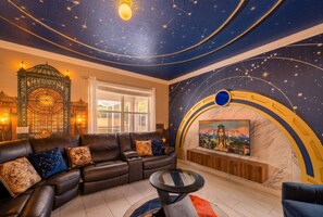 A living room with a sofa, a round coffee table, a fireplace, and a wall with a starry night design.