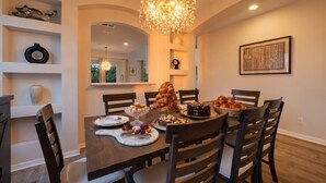 Uma sala de jantar com uma mesa de madeira posta para uma refeição, rodeada por cadeiras.
