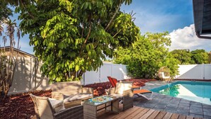 A wooden deck with wicker furniture, a pool, and a white fence.