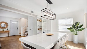 A modern kitchen with a central island, white cabinetry, and a hanging light fixture.