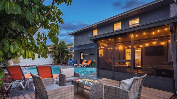 A modern outdoor living area with a pool, lounge chairs, and a dining table.
