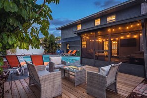 A modern outdoor living area with a pool, lounge chairs, and a dining table.
